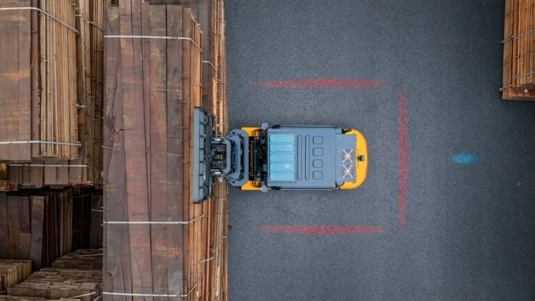 Bovenaanzicht van een Hyundai-heftruck tussen stapels hout met rode zoneverlichting op de vloer