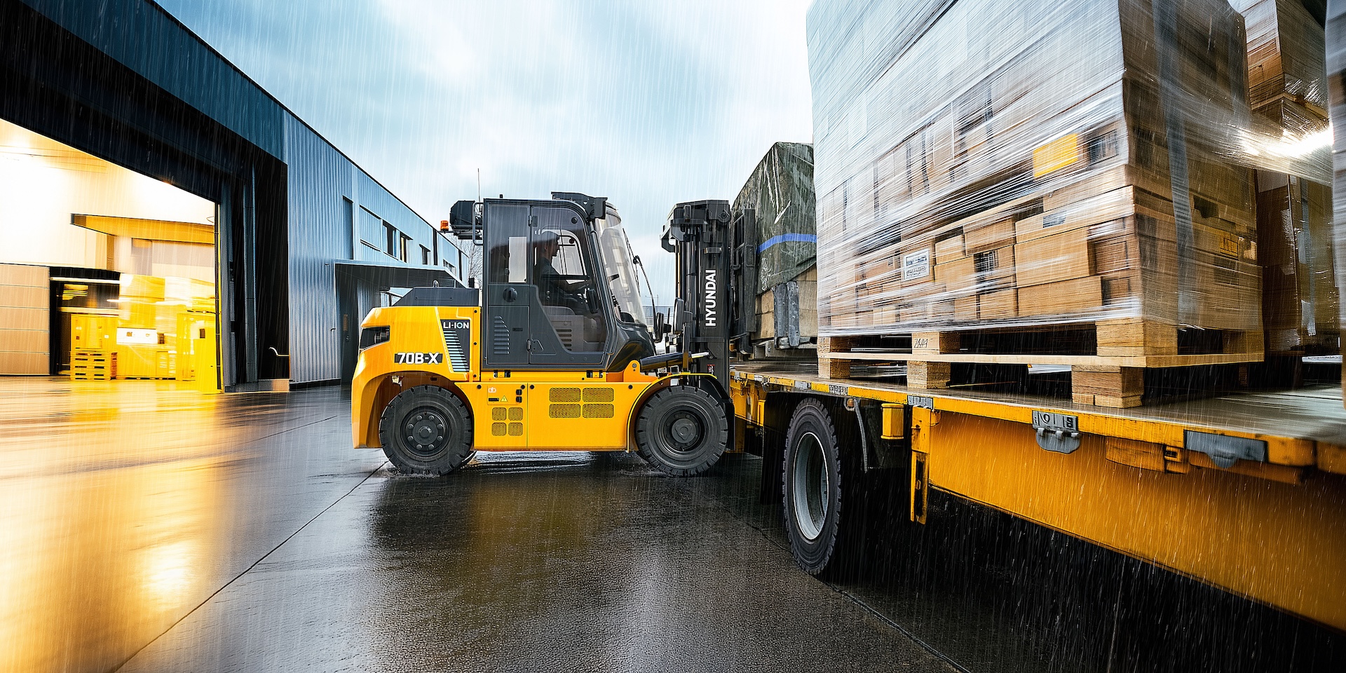 Hyundai 70B-X laadt een vrachtwagen in de regen