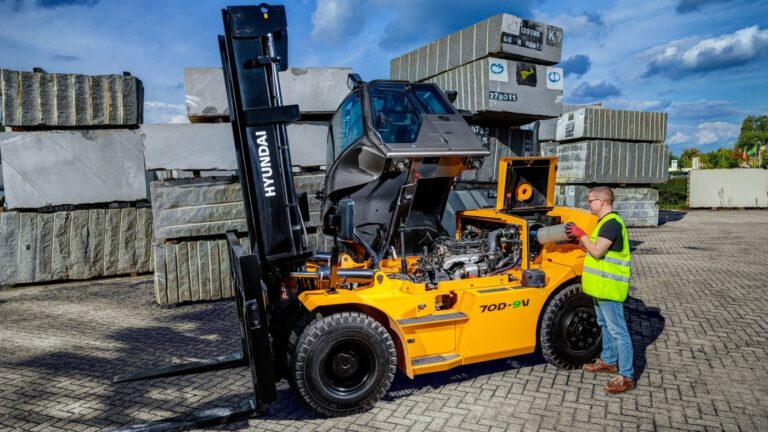 Hyundai 70D-9V dieselheftruck met betonblokken op een buitenterrein, met een medewerker in veiligheidskleding
